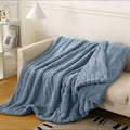 Chunky Knit Sherpa Throw Blanket — Blue draped over a cream sofa
